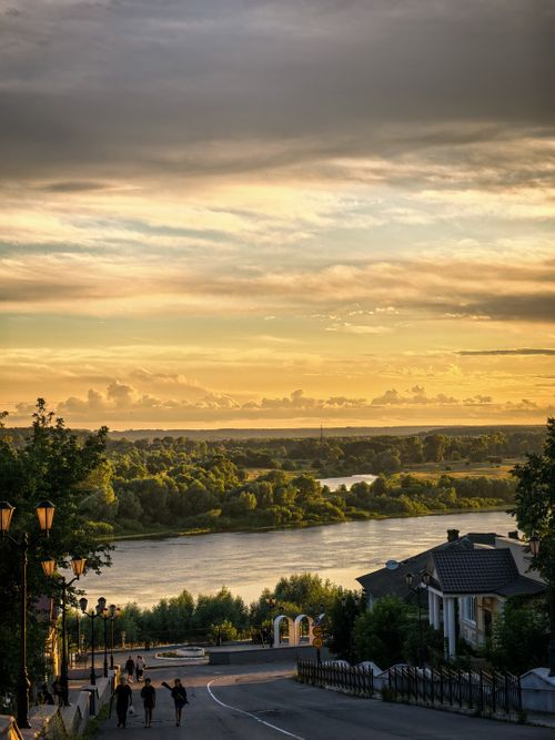 Free Enjoy a stunning sunset view over a quaint riverside town, framed by lush greenery. Stock Photo