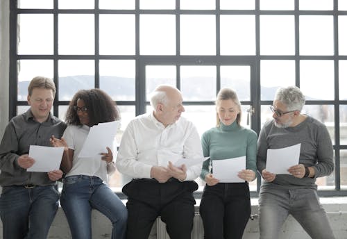 Free Happy diverse colleagues sitting with sheet of paper in afternoon Stock Photo