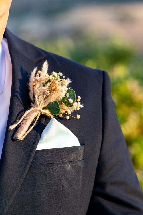 Free Close-up of a stylish boutonniere with dried flowers on a navy tuxedo jacket during daylight. Stock Photo