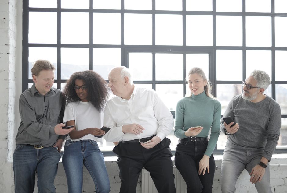 Photo by Andrea Piacquadio on Pexels A multicultural group of colleagues sitting indoors sharing smartphones creating a friendly team atmosphere.