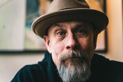 Free Close-up portrait of a mature man with a beard wearing a fedora hat, evoking a vintage style. Stock Photo