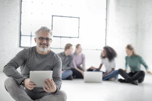Free Group Of People Sitting On The Floor With Focus On Man Holding A Digital Tablet Stock Photo