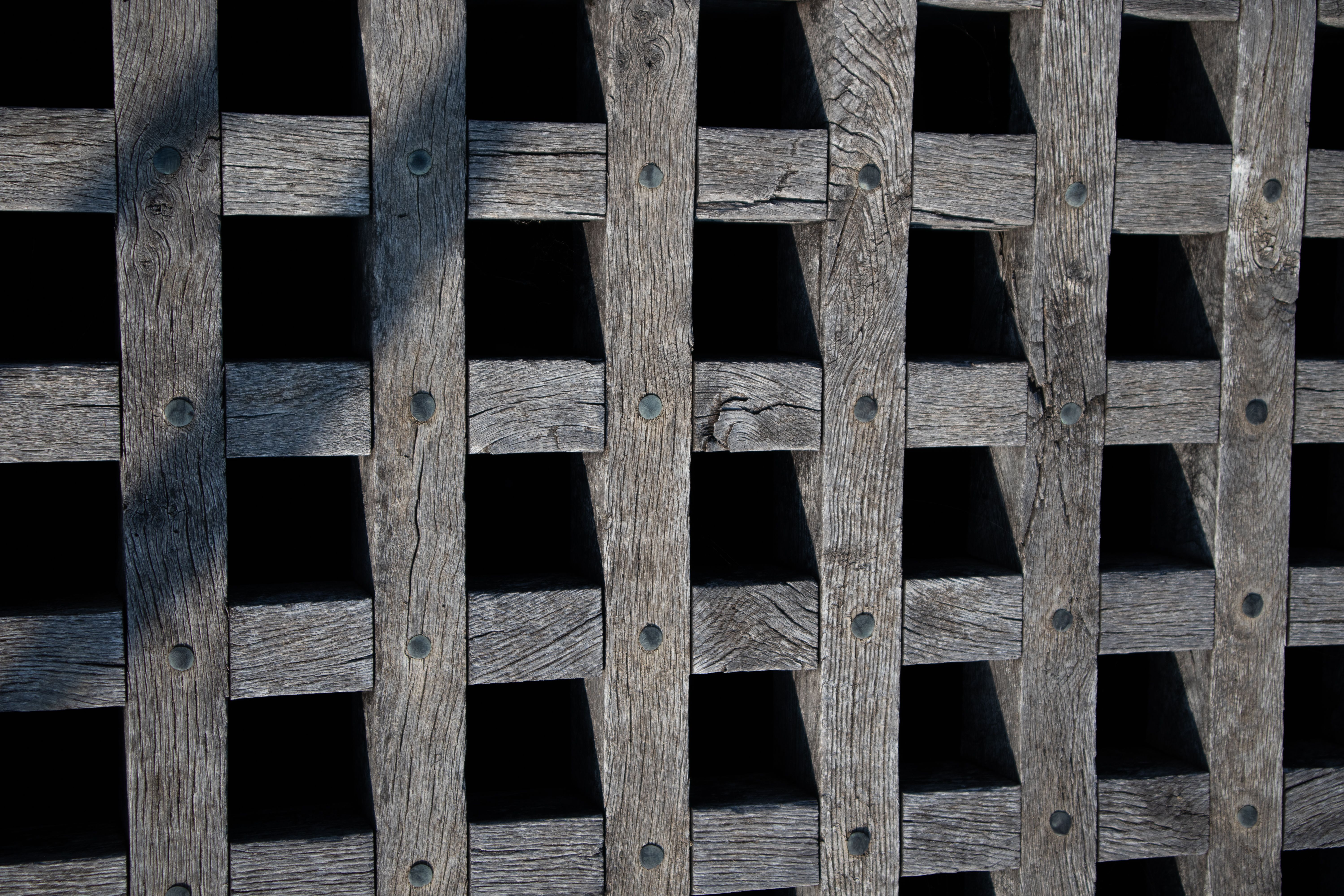 Rustic wooden grid with intricate pattern and dark shadows, offering a textured architectural detail.