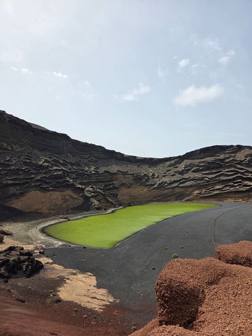 Free Unique green lagoon in El Golfo, Lanzarote surrounded by volcanic landscape under a bright sky. Stock Photo
