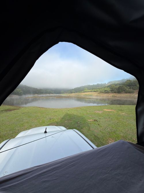 Free Serene view of the lake and greenery viewed from a car trunk camping setup. Stock Photo