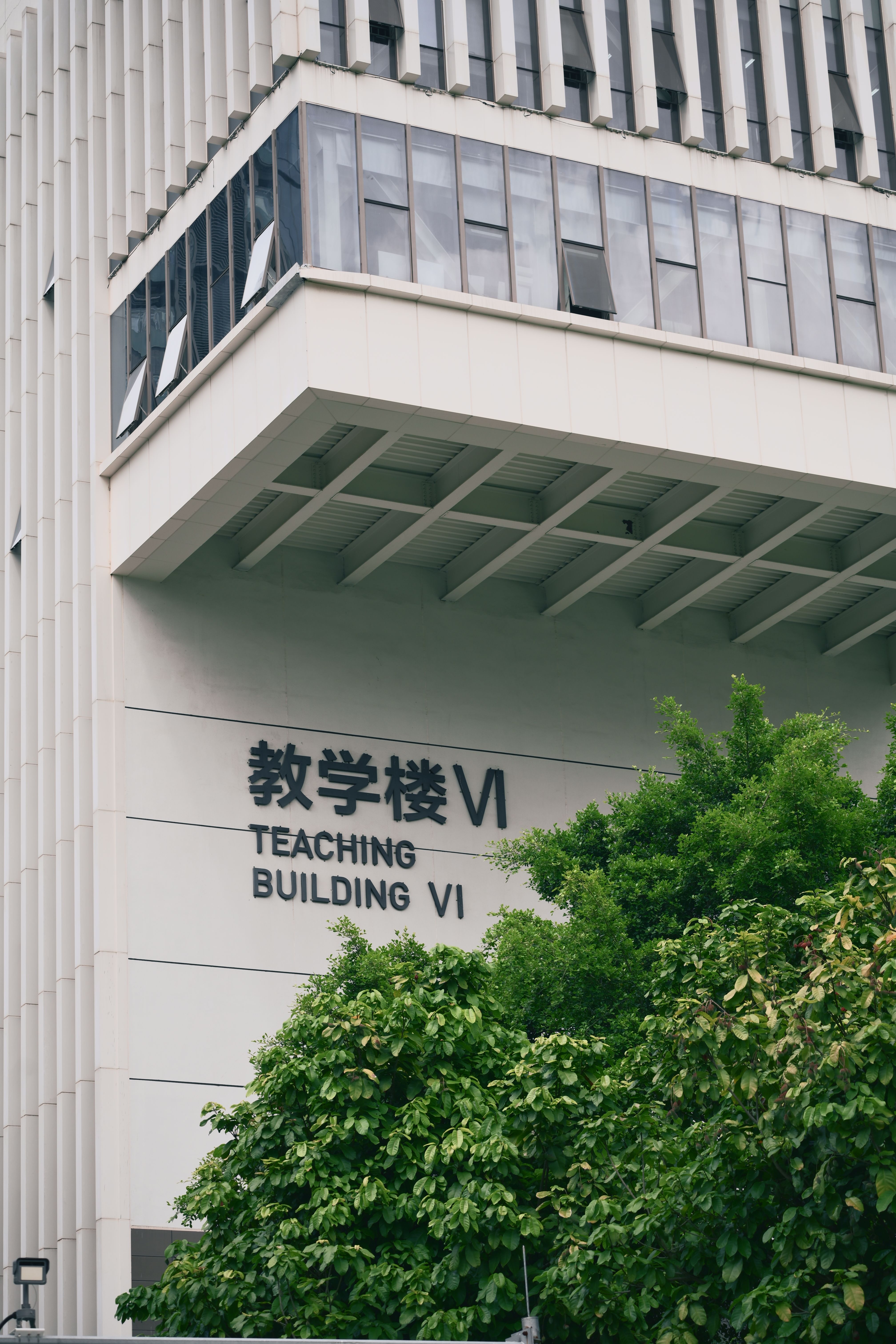 A contemporary teaching building exterior partially covered by lush greenery.