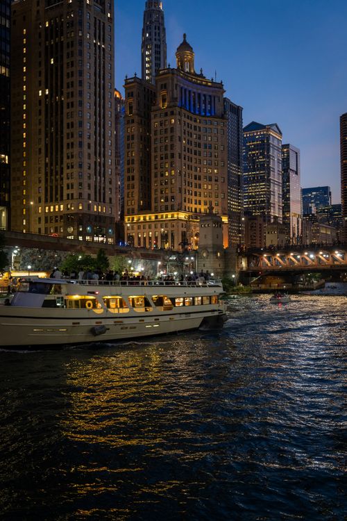 Free A scenic evening boat tour on the vibrant Chicago River with illuminated skyscrapers and a clear sky. Stock Photo