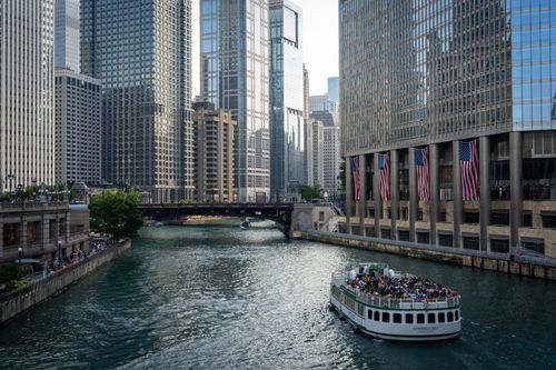 Free A boat navigates the Chicago River surrounded by skyscrapers and city architecture. Stock Photo