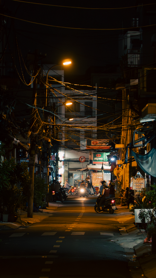 Free Urban night street with motorbike, street lights, and visible wiring, evoking a moody urban atmosphere. Stock Photo