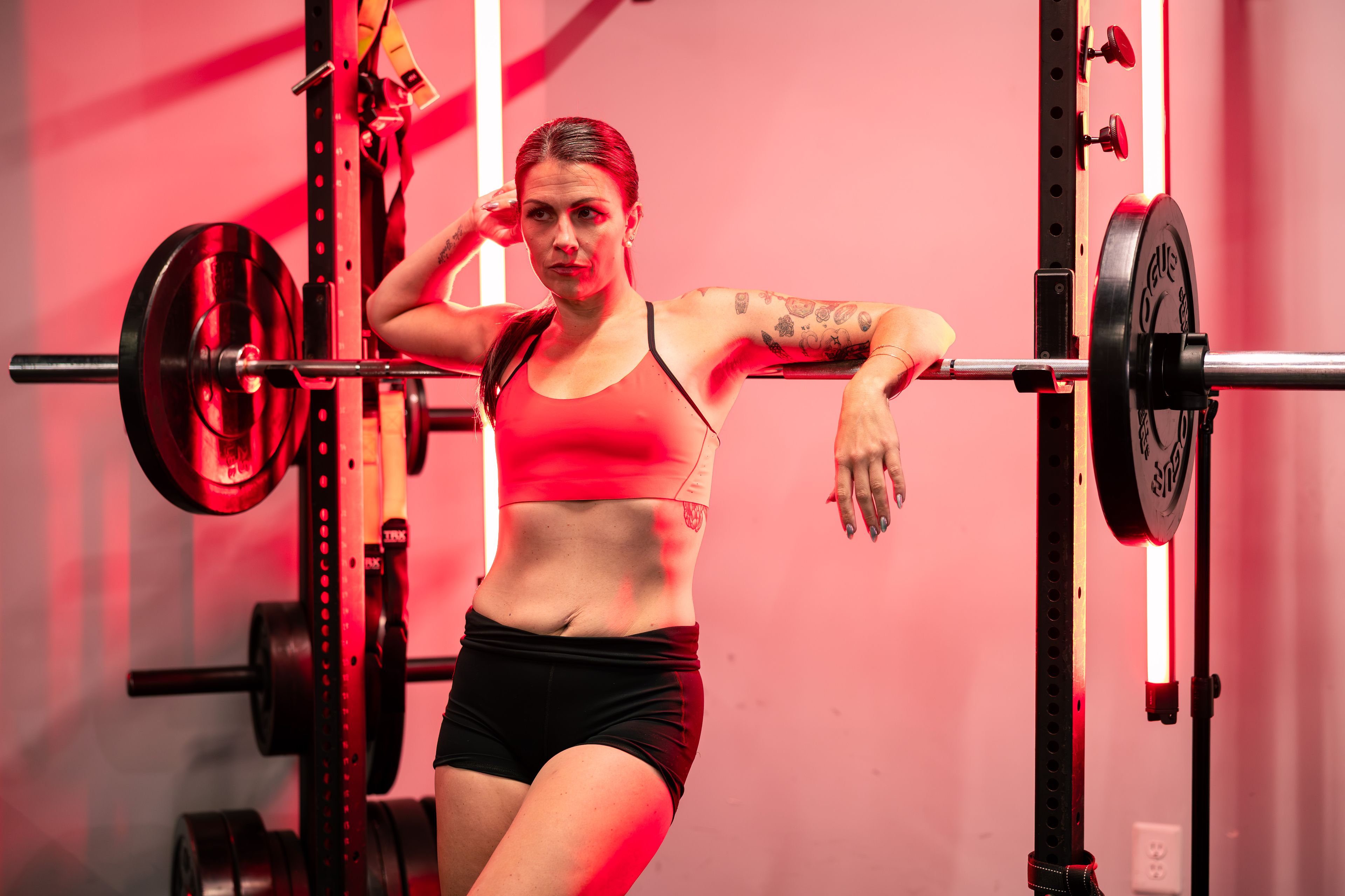 A determined woman in a gym setting, showcasing strength and athleticism with a barbell.