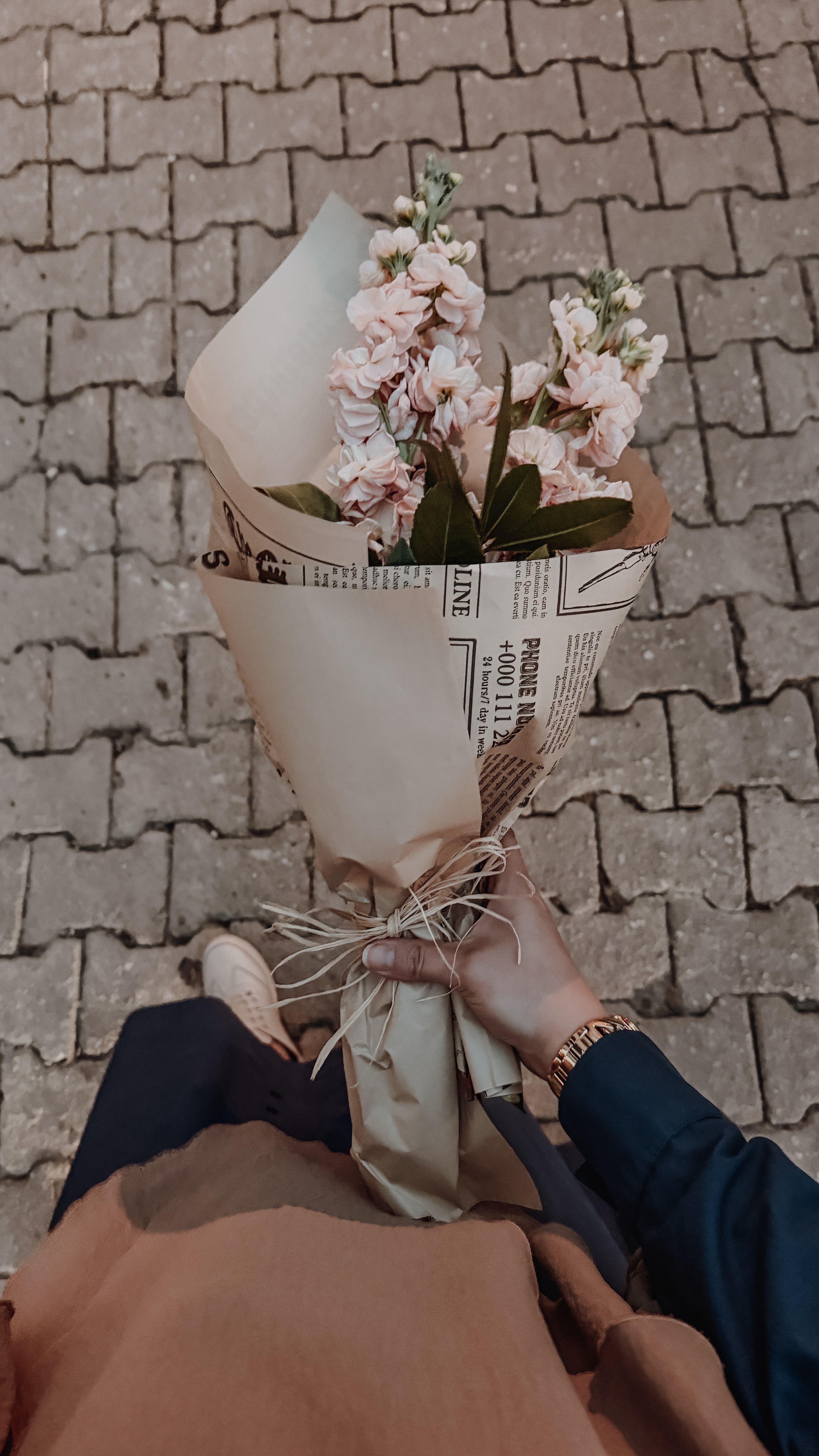 A vibrant bouquet wrapped in newspaper held over a paved street in Istanbul, Turkey.