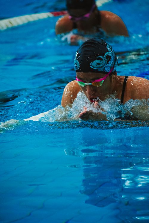 Free A focused swimmer competes in a breaststroke race at an indoor swimming pool, making waves. Stock Photo