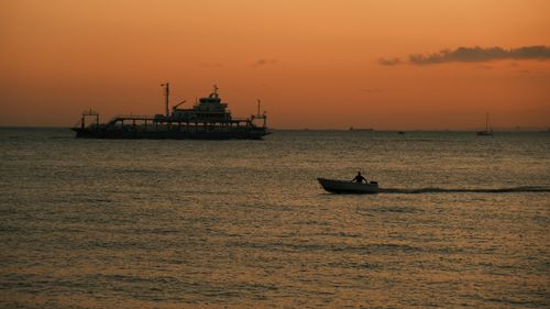 Free A tranquil scene of boats on the Bali sea during a stunning sunset, perfect for travel and nature themes. Stock Photo