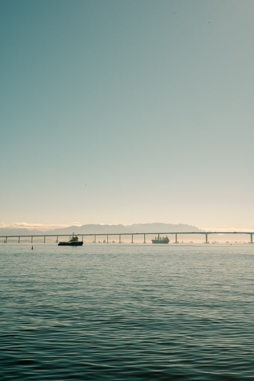 Free Tranquil water scene with a boat and distant bridge under a clear sky. Stock Photo