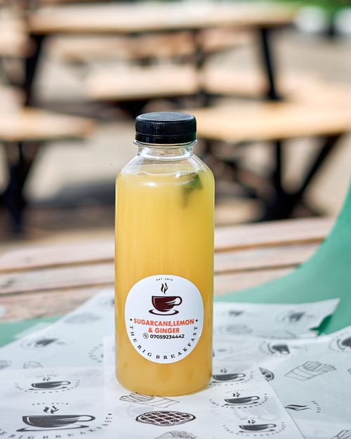 Free A bottle of sugarcane, lemon, and ginger juice on a table outdoors. Stock Photo