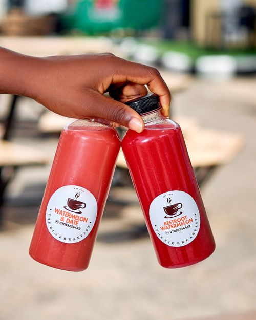 Free Close-up of two juice bottles containing watermelon and beetroot flavors, held outdoors. Stock Photo