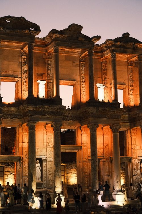 Free Ancient Celsus Library illuminated at sunset, featuring visitors exploring its historic ruins. Stock Photo