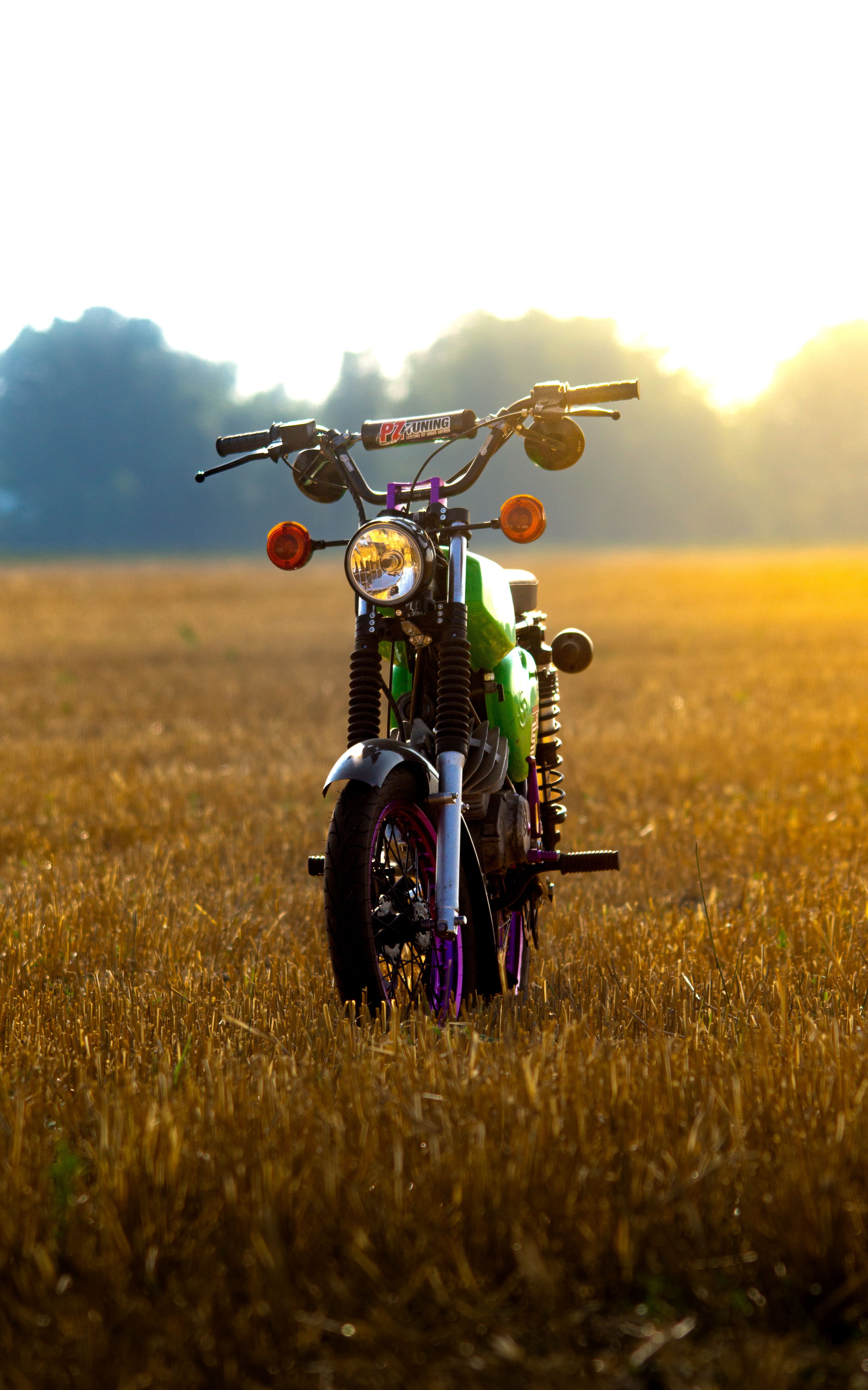 A classic motorcycle standing in a sunlit field at sunset in Schönwald, Germany.