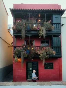 A vibrant red house with lush balcony flowers in La Palma, Spain, captures the essence of Mediterranean architecture.