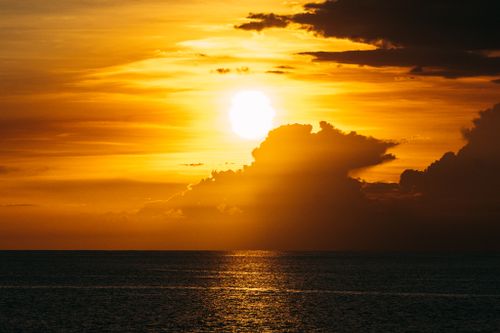 Free A breathtaking sunset scene with golden hues painting the sky over a calm ocean horizon, evoking tranquility. Stock Photo