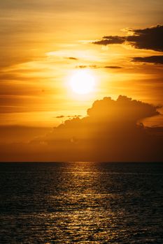 Stunning sunset over the ocean with dramatic golden clouds and shimmering water reflections.