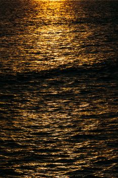 Captivating image of golden sunlight reflecting on ocean waves at sunset, creating a serene and warm ambiance.