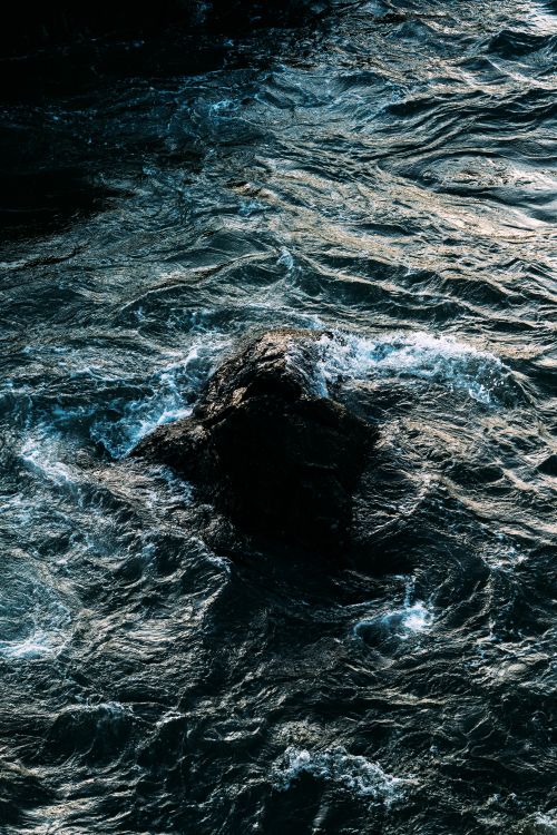 Free Dramatic capture of ocean waves crashing against a rock at twilight, highlighting nature's power and beauty. Stock Photo