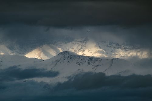 Free Moody mountainous landscape with snow-clad peaks and atmospheric clouds under a dramatic sky. Stock Photo