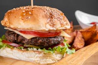 木板上放着美味的芝士汉堡，上面有新鲜的配料和土豆角