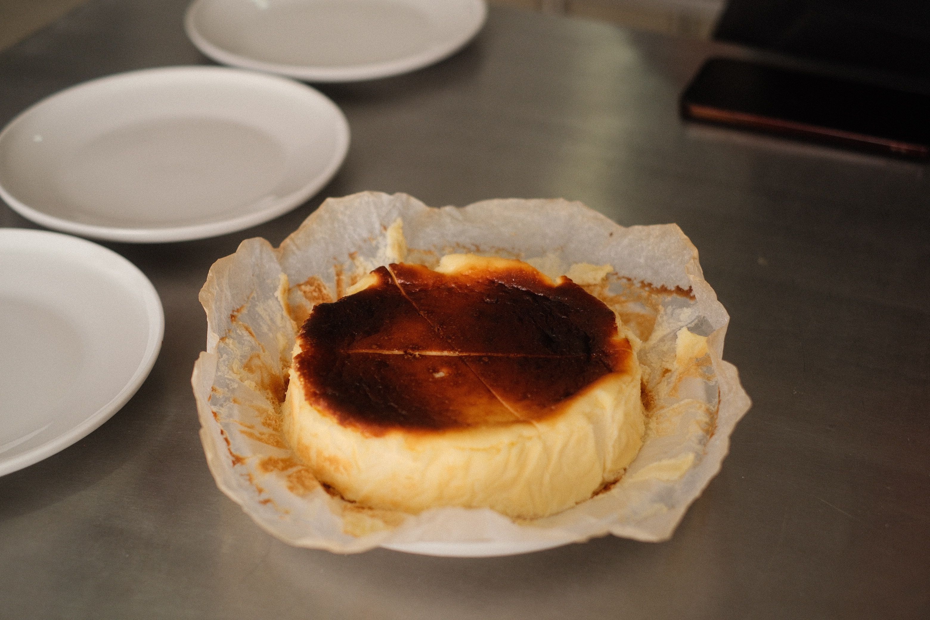 slice of burnt basque cheesecake on a small ceramic plate beside an espresso cup