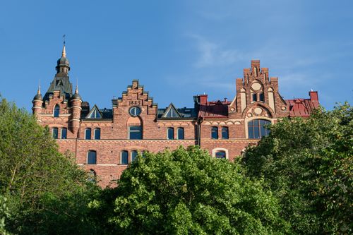 Free A stunning historic brick building with intricate architectural details, surrounded by lush greenery. Stock Photo