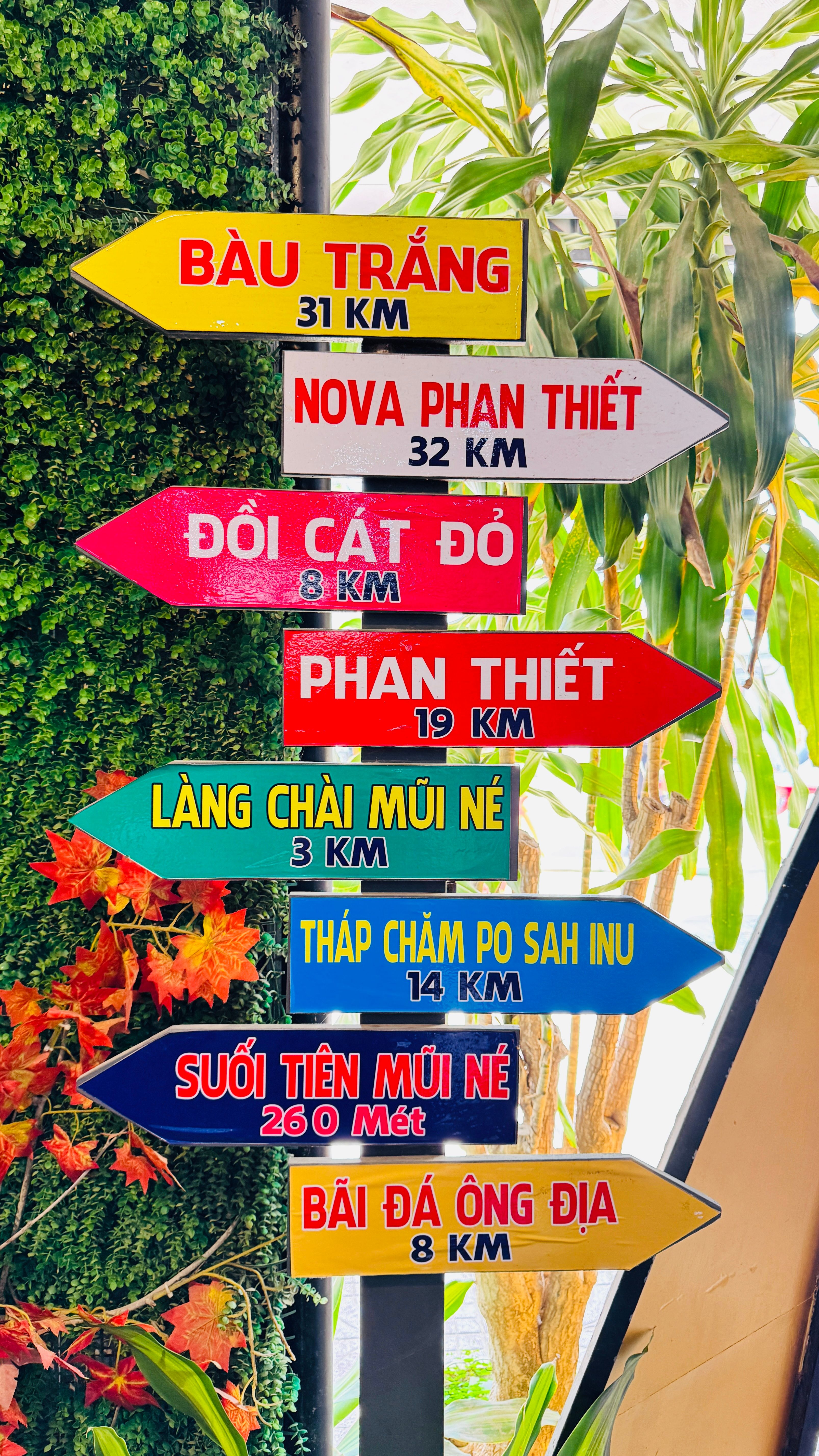 Brightly colored direction signs in Vietnam with distances to nearby attractions and landmarks.