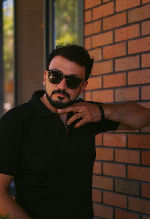 Free Confident man in sunglasses poses against a brick wall outdoors. Stock Photo
