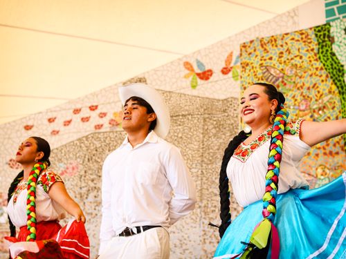 Free Colorful Mexican folk dancers in traditional attire performing outdoors with joyous expressions. Stock Photo