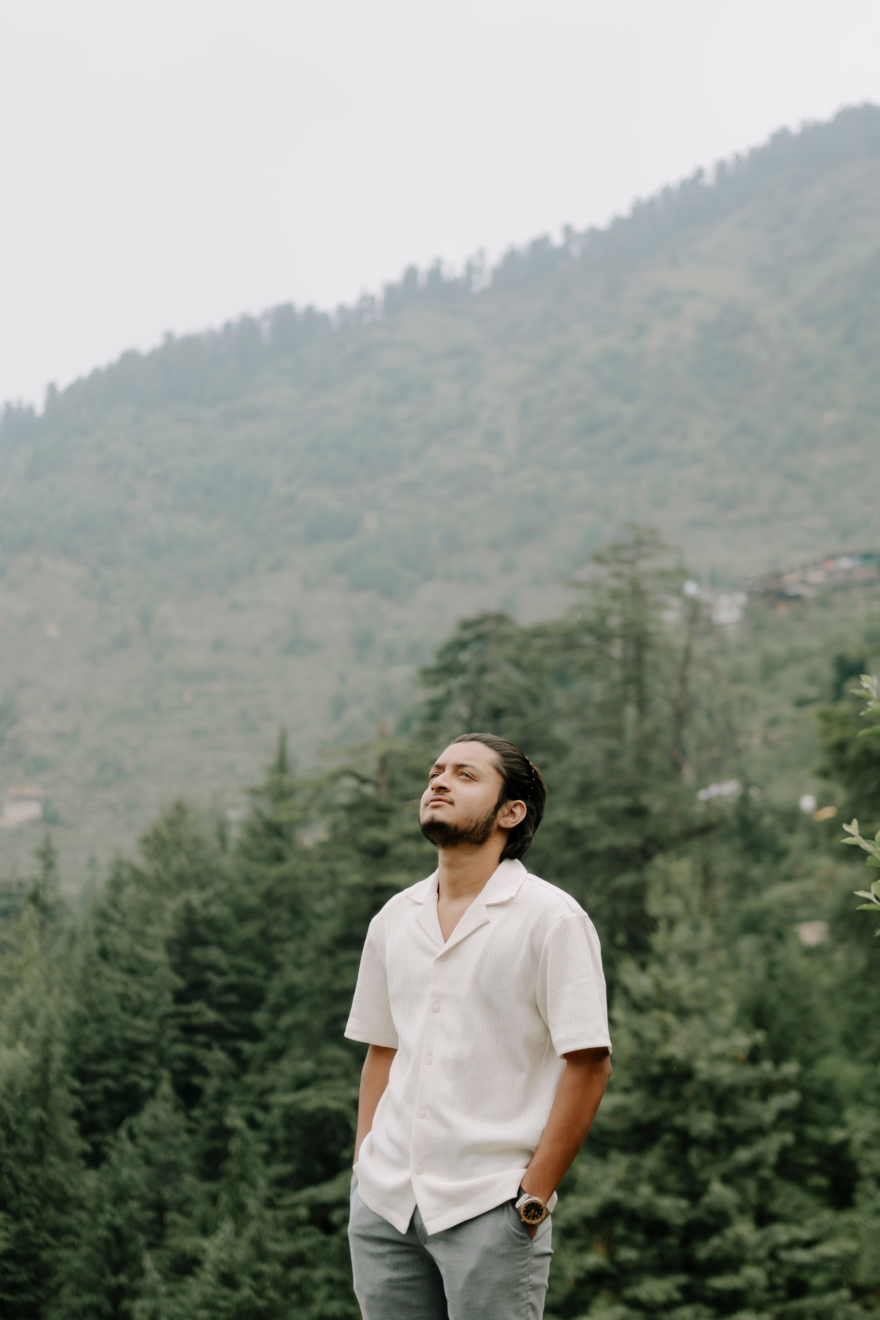 A man enjoys tranquility in lush Indian mountains, evoking a sense of peace and adventure.