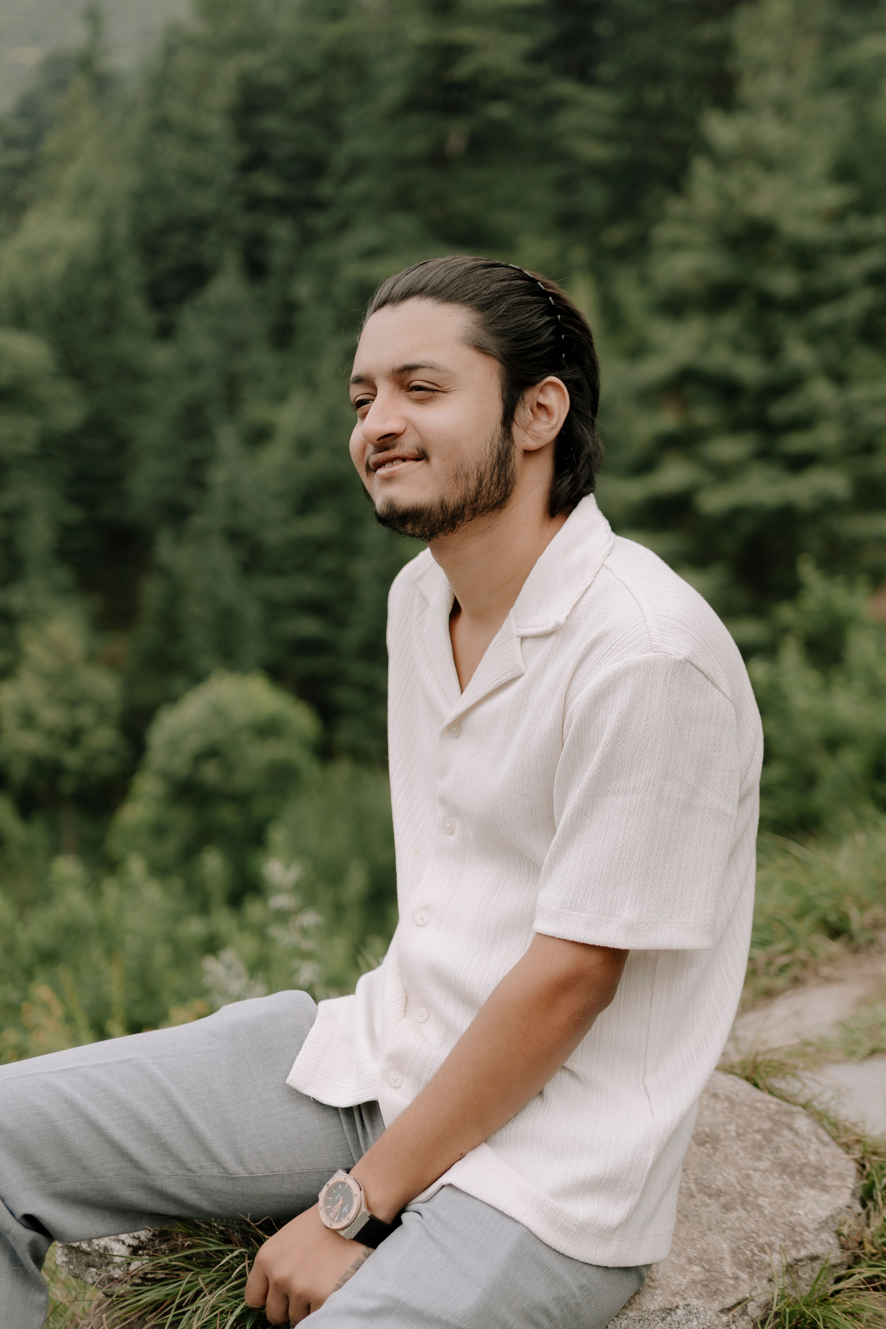 Portrait of a young man sitting outdoors in an Indian forest, enjoying nature.