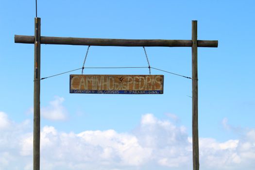 Wooden sign on a clear day marking the Caminho das Pedras trail in Guaratuba, Paraná, Brazil.