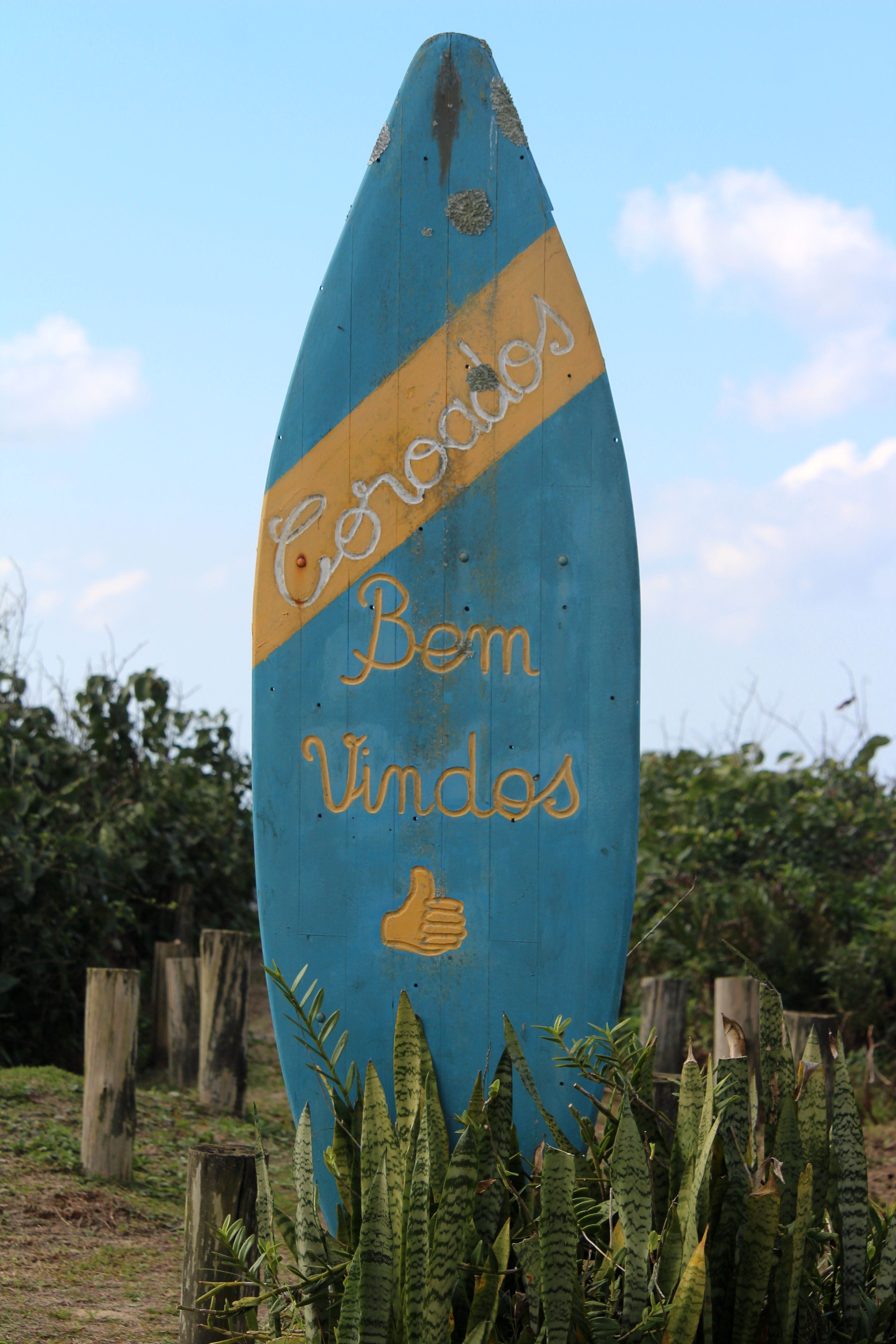 A vibrant wooden surfboard sign greeting visitors at Guaratuba, Paraná, Brazil beach.