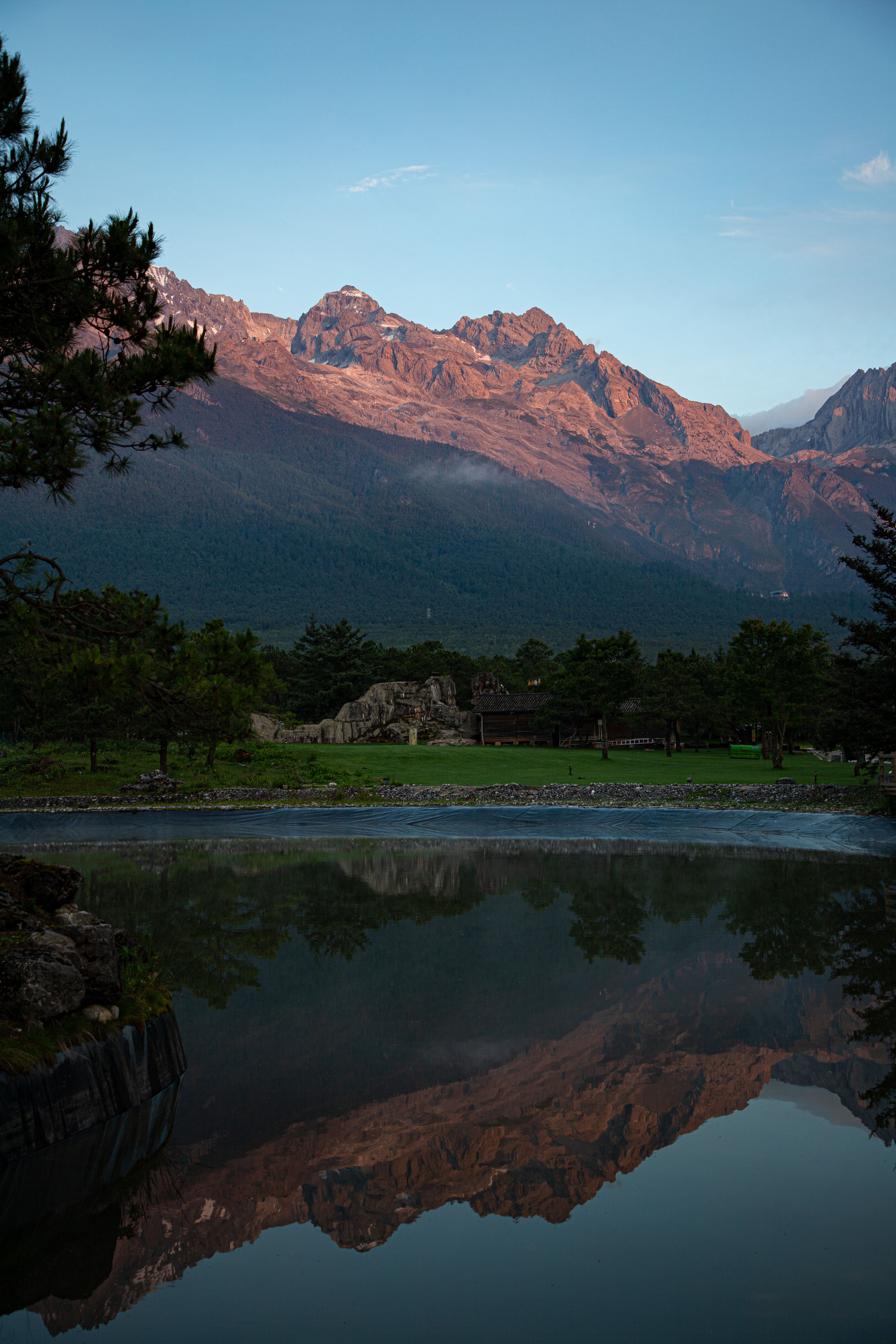 Breathtaking sunrise view of Jade Dragon Snow Mountain reflecting in tranquil waters, Lijiang, China.