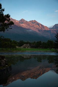 Breathtaking sunrise view of Jade Dragon Snow Mountain reflecting in tranquil waters, Lijiang, China.