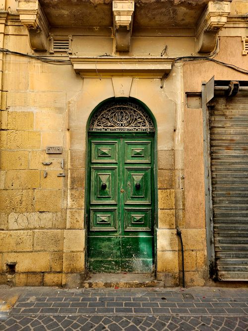 Free A vibrant green door on a historic stone facade in an urban street setting. Stock Photo