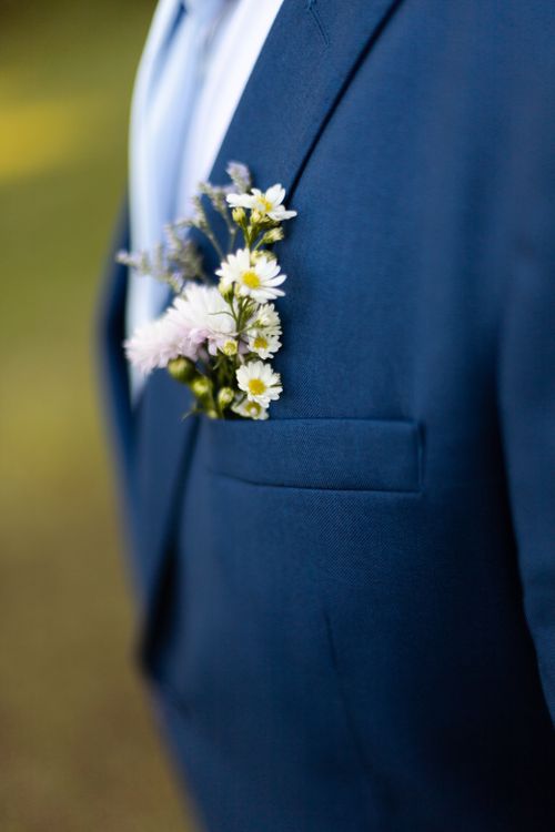 Free Close-up of a groom's blue suit with a floral boutonniere, symbolizing love and elegance. Stock Photo