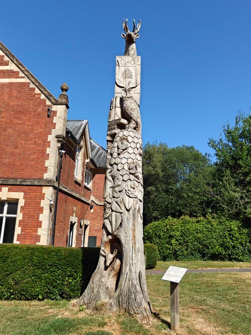 Free Detailed wooden tree sculpture outside a historical brick building under a clear blue sky. Stock Photo