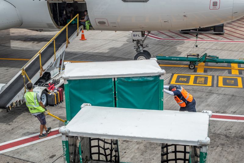 Ground crew in high visibility vests loading baggage onto an aircraft