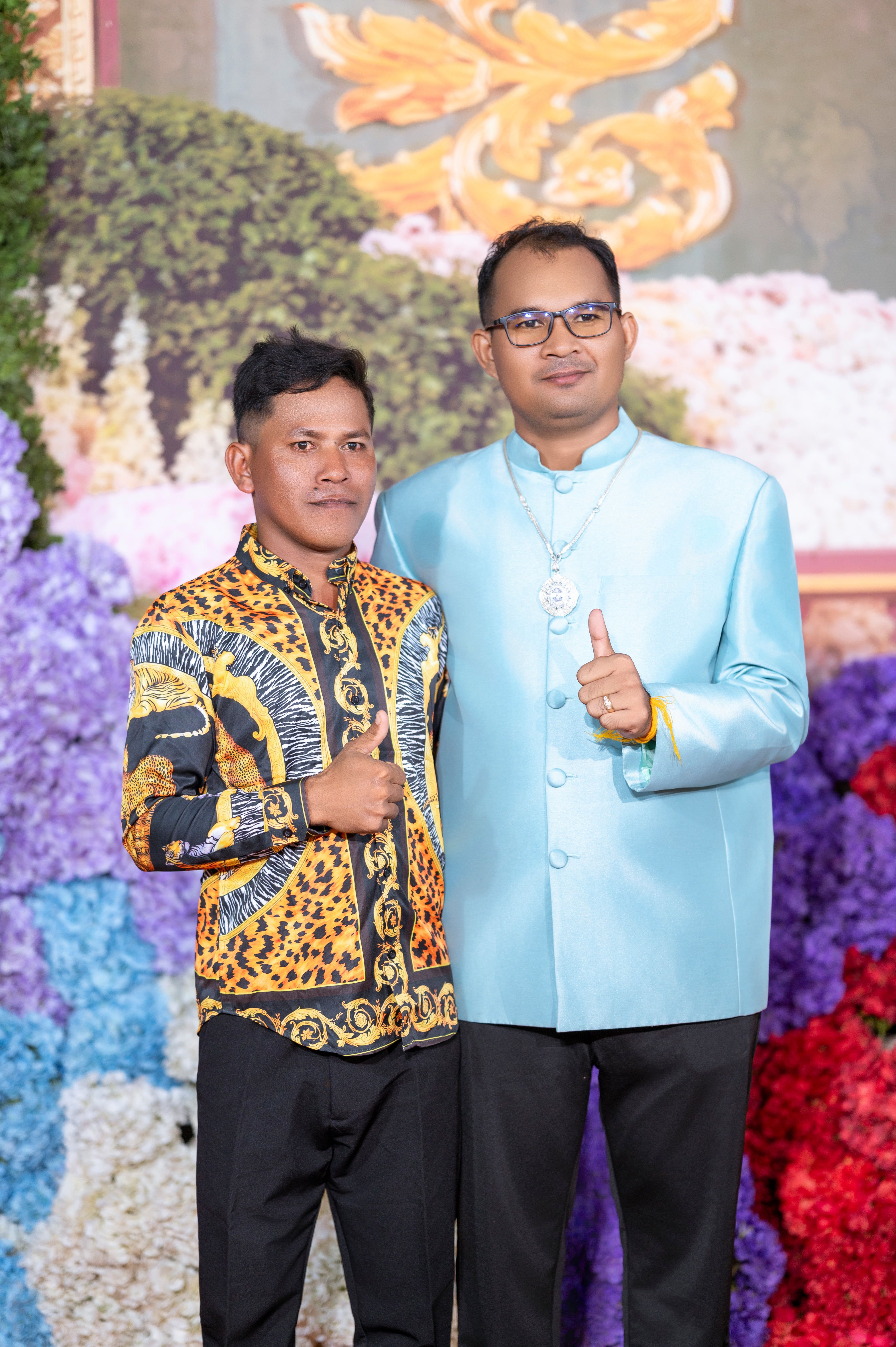 Two men in vibrant traditional attire at a wedding in Cambodia.