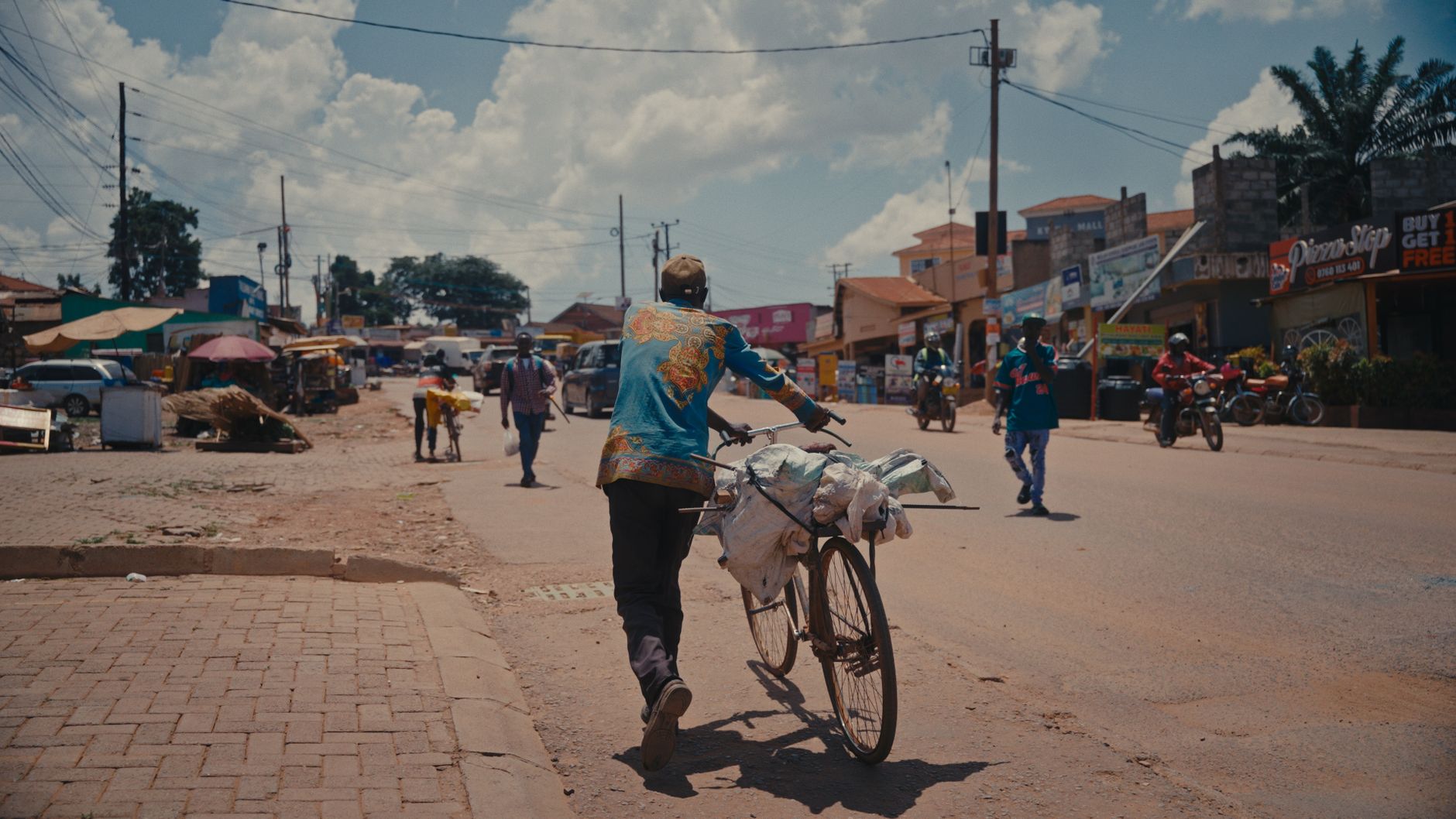 A vibrant street scene in Uganda showing daily life with people and bicycles