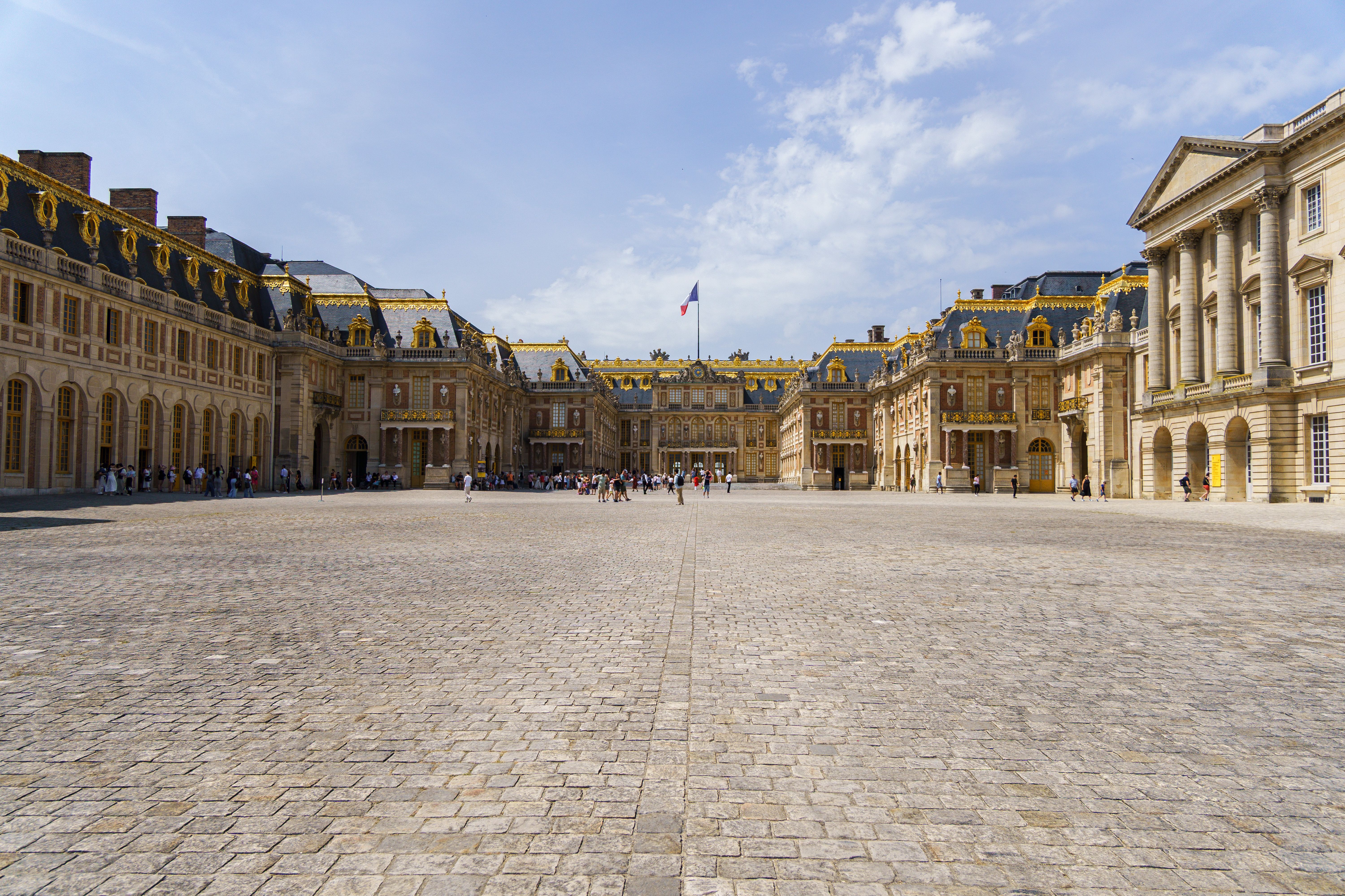 Exterior of the Palace of Versailles under a clear blue sky.