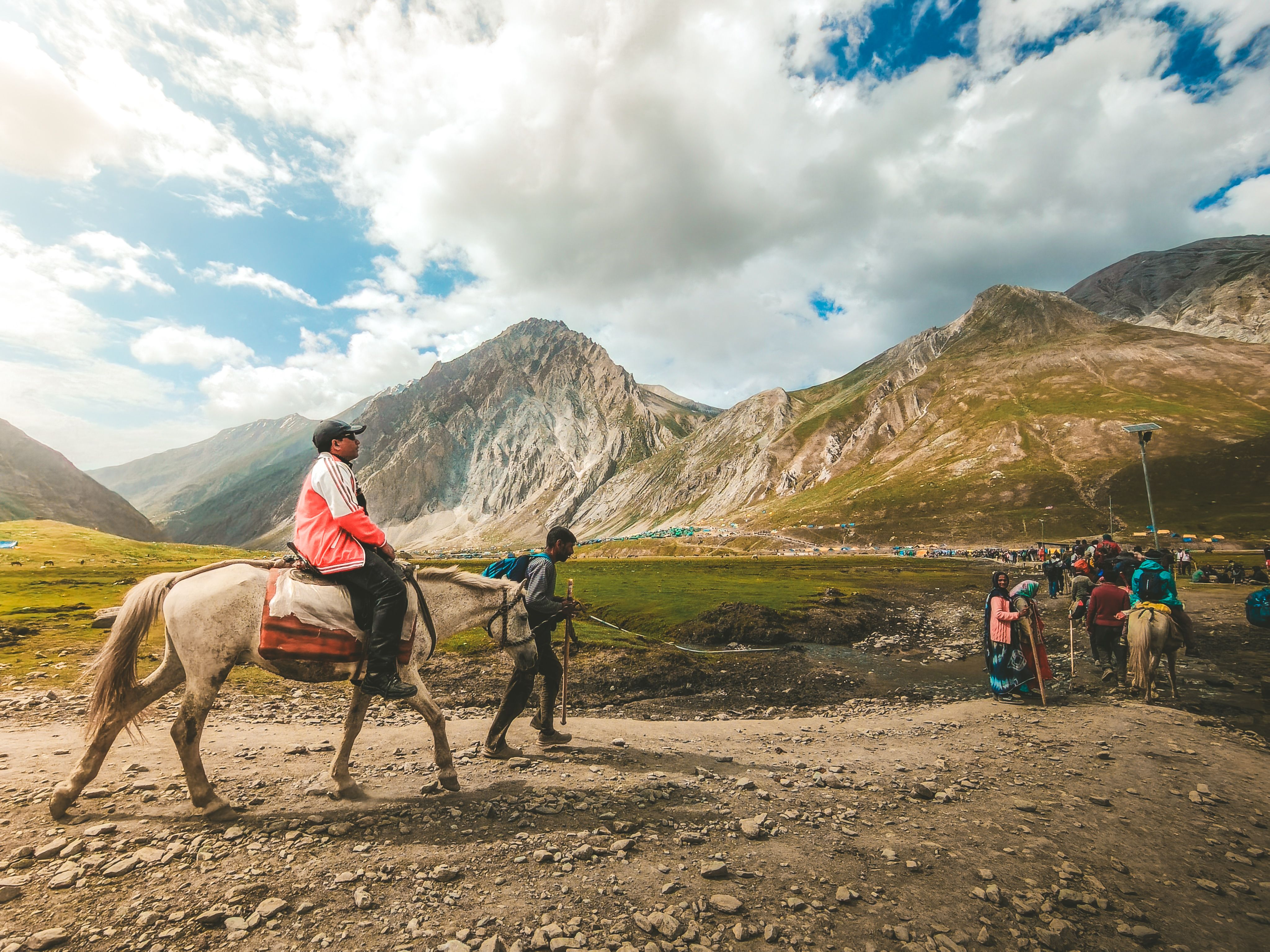 Travelers ride horses through a mountainous landscape, capturing an adventurous journey.