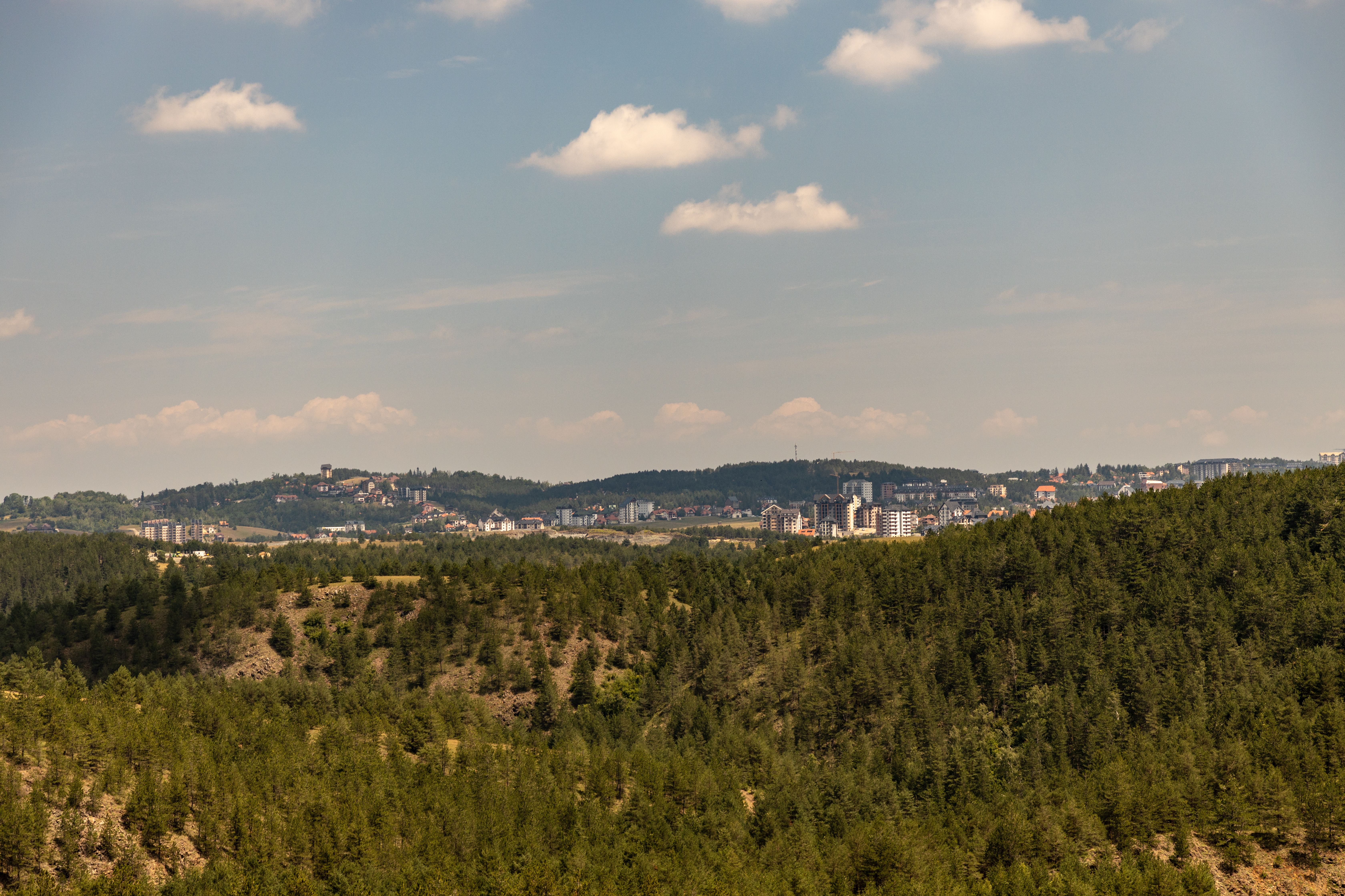 Serene view of Zlatibor's lush hills and distant town, capturing the natural beauty and tranquil atmosphere.