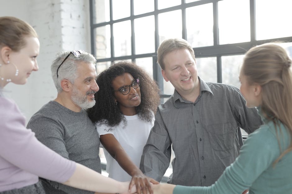 Cheerful diverse colleagues joining hands after coming to agreement